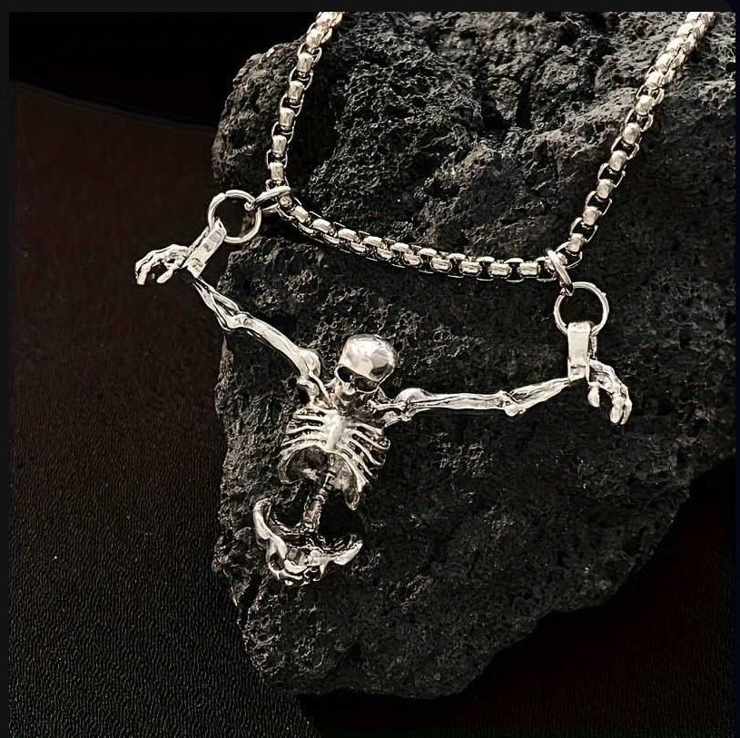 a skeleton hangs on a chain on a dark rock